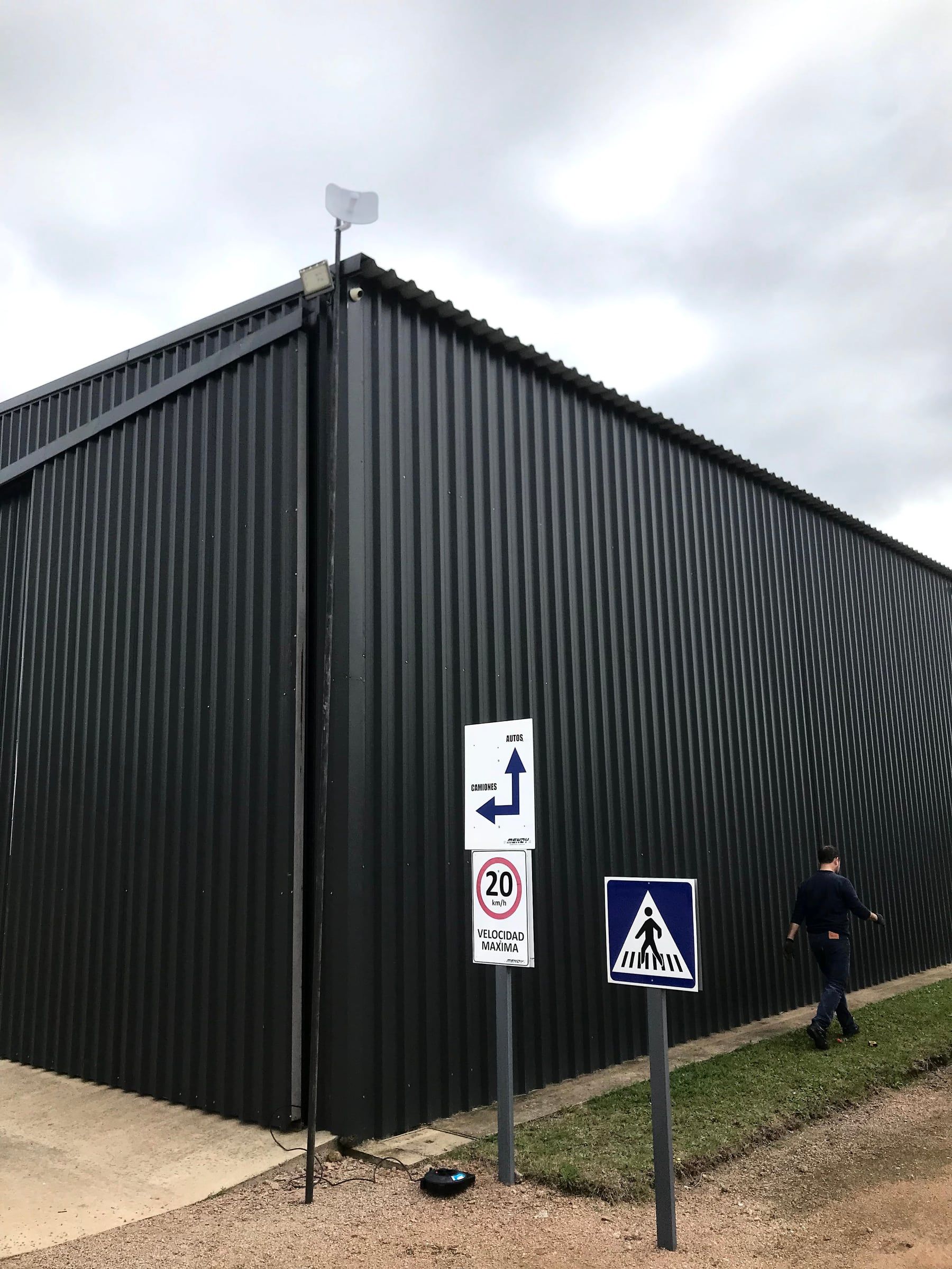 Radio on a corner-mounted mast with the feed cable run down the building edge to the equipment room.