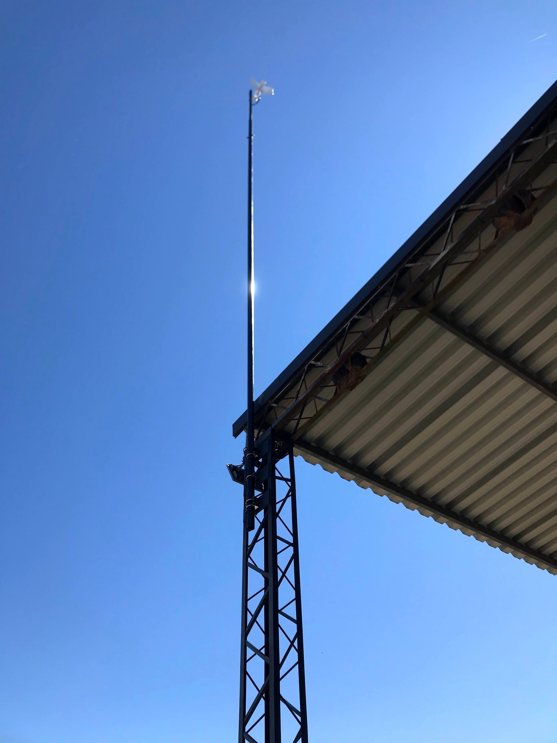 Looking up a lattice mast to the 5 GHz radio mounted at the top, clear of the building roofline.