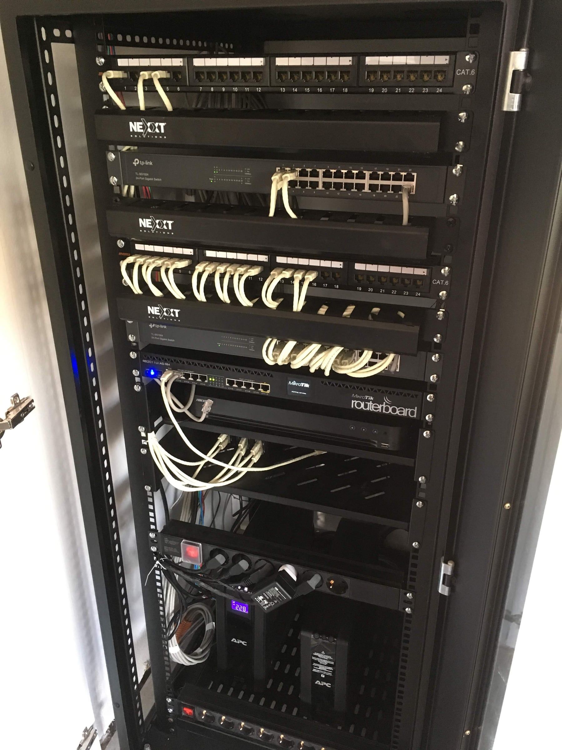 Rack build: two 24-port CAT6 patch panels, managed switches and a MikroTik router, on UPS-protected power.